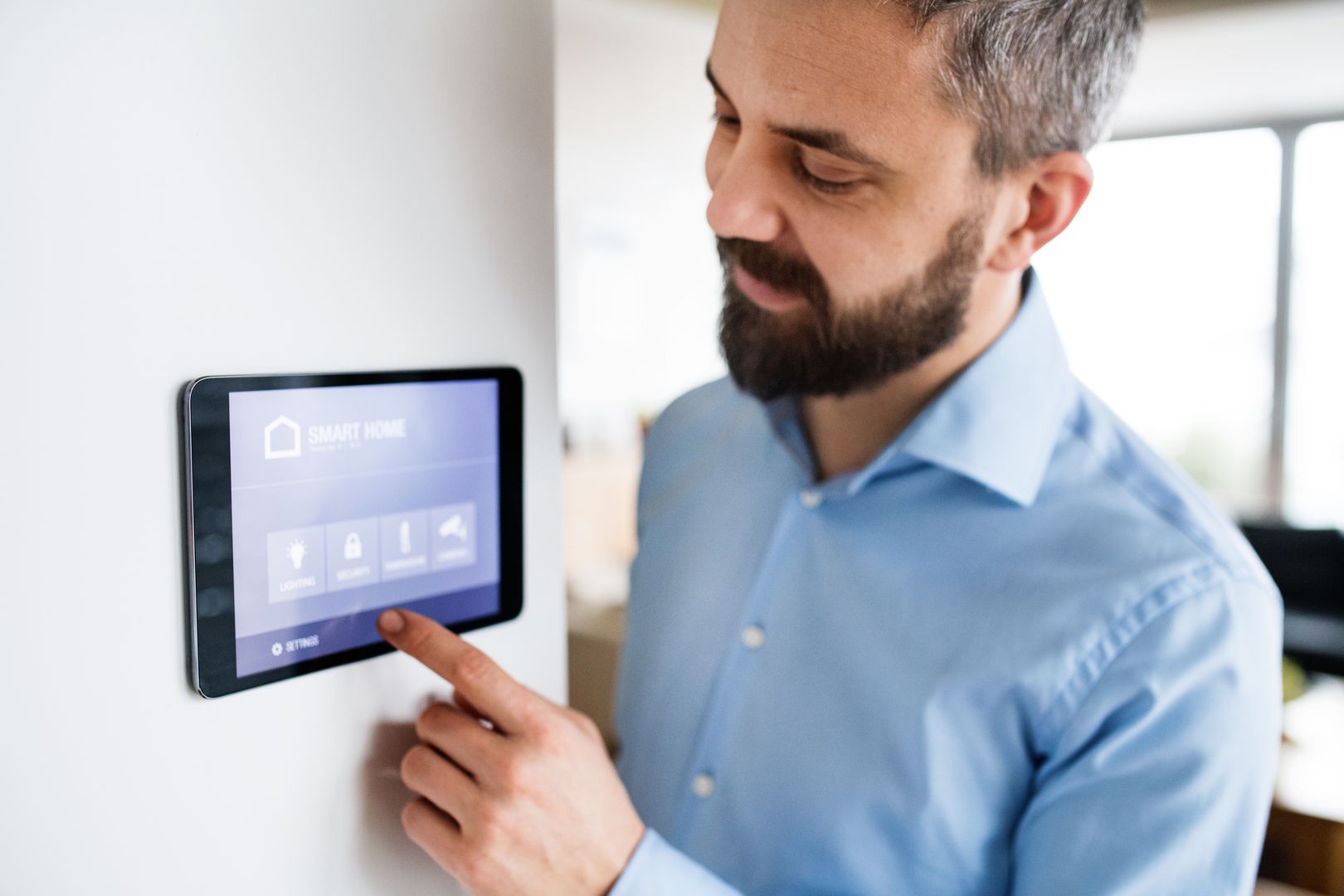 Ein Mann bedient ein Tablet, welches an einer Wand hängt